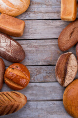 Artisan bakery border background. Organic farmers bread and buns on rustic wooden background. Top view, copy space.