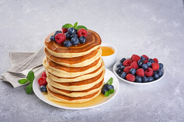 Pancakes with fresh berry and honey on gray background. Healthy breakfast.