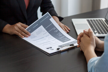 A newly graduated woman submits a resume for the owner of the company to request that they be considered for work qualifications.