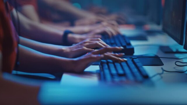 Diverse Esport Team of Pro Gamers Playing in Video Game on a Championship. Focus on Hands, Keyboards and Mouse. Stylish Neon Cyber Games Arena. Online Streaming of Tournament Event. 