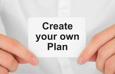 Man's hands take a card with words Create your own plan, finance and business concept.