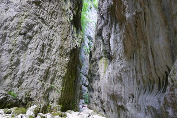 person walking between high rocks on a riverbed