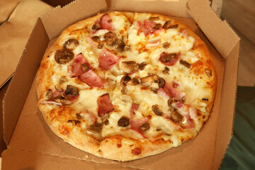 Freshly baked delivery pizza in plain open box