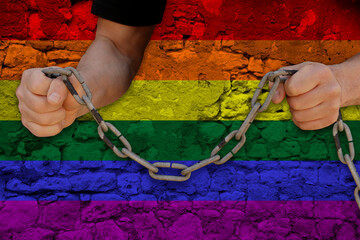 male hands break the iron chain, a symbol of bondage,protest against the background of LGBT rainbow...