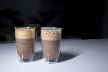 two cups of coffee in double-botoom glass on white table in gray kitchen. High quality photo