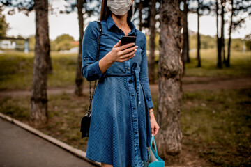 Woman with face mask walking down the street using phone