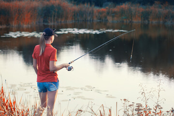 Cute woman is fishing with rod on lake