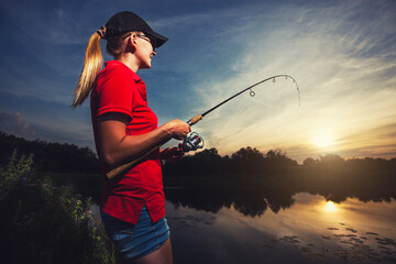Cute woman is fishing with rod on lake