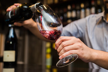 Waiter pouring red wine in a glass.