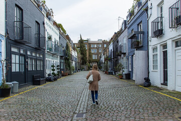 Girl walking in a residential street in London, UK. Block of London houses. English architecture. Elegant apartment buildings. Real estate concept urban scene.European style of living