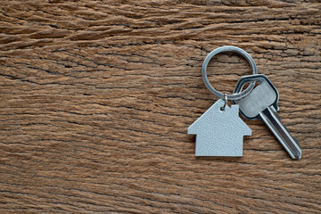 Silver key house with house shaped keychain on vintage wooden table background.