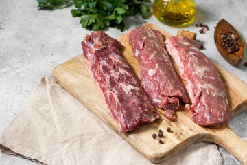 Lamb meat. Young lamb meat on a wooden Board on the light gray kitchen table. Raw lamb meat and cooking ingredients. Lamb tenderloin