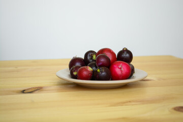 Many colorful raw radish in brown plate, bright purple vegetables on wooden table. Healthy vegetarian and organic kitchen concept