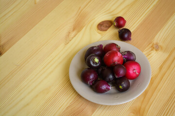Many colorful raw radish in brown plate, bright purple vegetables on wooden table. Healthy vegetarian and organic kitchen concept
