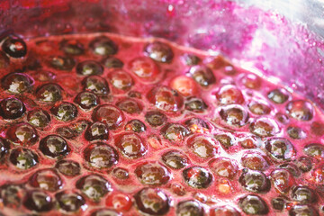 Background with black currant jam boiling in a saucepan