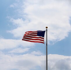 The american flag with the white clouds and blue sky.