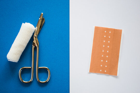 Medical bandage, scissors and hansaplast on blue and white background