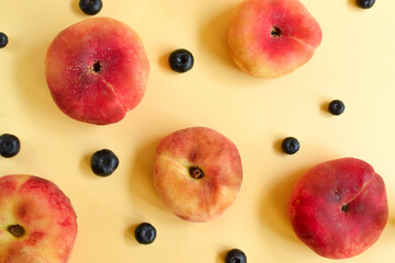 Peach on a yellow background. Juicy ripe peach and blueberry. Creative minimalistic food concept.