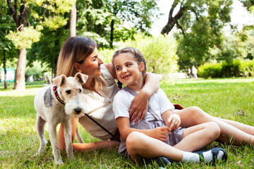Obraz premium young pretty caucasian mother walking with little cute daughter and dog fox terrier, lifestyle people concept