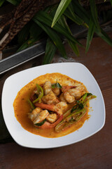 Stir fried shrimp with curry paste in a white plate.
