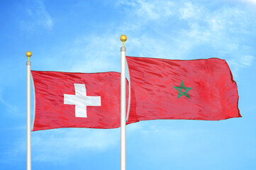 Switzerland and Morocco two flags on flagpoles and blue sky