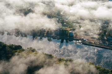 Fototapeta na wymiar Airscape - The thick clouds are hovering over the city. The city-view with long bridge over the river, deep forest and dollhouses peeked out as the clouds hurried past