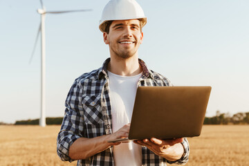 An electrical engineer standing on a field with windmills