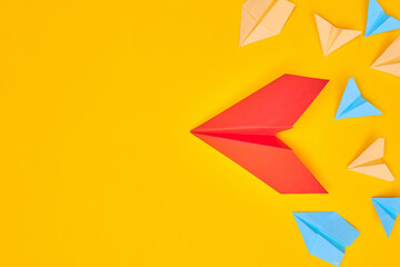 red paper plane and others on a yellow background. Leadership, teamwork and courage concept. Flat layer copy space