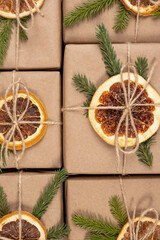 Christmas or New Year's pattern from boxes in craft paper with dried oranges, spruce branches and twine close-up. Concept Zero waste, eco friendly Merry Christmas. Top view Flat lay