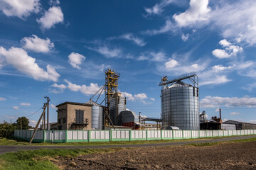 Obraz premium Modern Granary elevator. Silver silos on agro-processing and manufacturing plant for processing drying cleaning and storage of agricultural products, flour, cereals and grain.