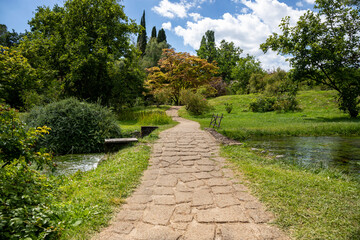 Obraz premium Garden of Ninfa and the pathway made with cobblestones, in Italy in the province of Latina. Most beautiful and romantic gardens in the world.