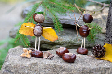 Angel and devil figures made from chestnuts and safety matches and dry leaves in the garden