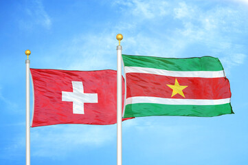 Switzerland and Suriname two flags on flagpoles and blue sky