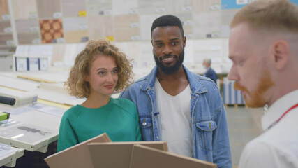 Obraz premium Couple at interior decor store talking with seller manager about flooring