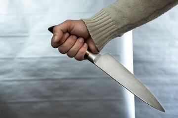 An evil man holds a shiny steel knife in his hand, a killer in action. A maniac is hunting a victim.