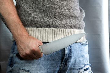 An evil man holds a shiny steel knife in his hand, a killer in action. A maniac is hunting a victim.