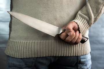 An evil man holds a knife behind his back, waiting for the victim. A maniac and a rapist with a gun.