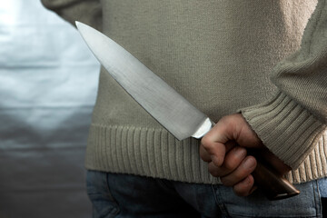 An evil man holds a knife behind his back, waiting for the victim. A maniac and a rapist with a gun.