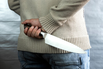 An evil man holds a knife behind his back, waiting for the victim. A maniac and a rapist with a gun.