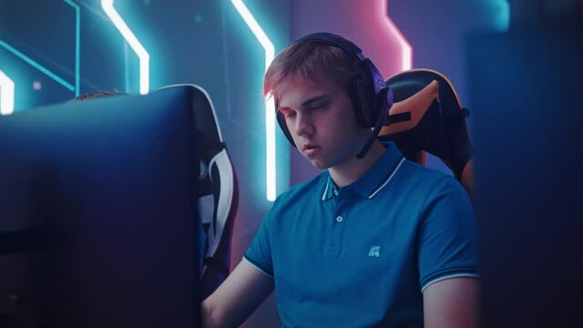 Professional Gamer Plays Computer Video Game Talking into Headset with Teammates on a Championship
