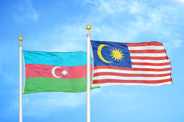 Azerbaijan and Malaysia two flags on flagpoles and blue sky
