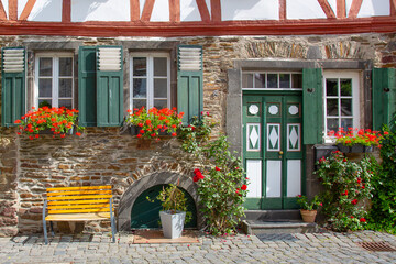 Facade of an old half-timbered house with flowers and a bench in front