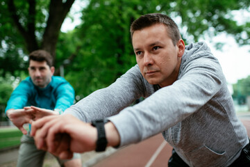 Young men exercising on a race track. Two young friends training outdoors..