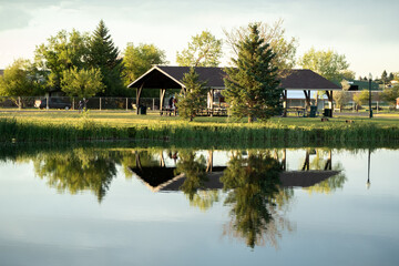 Picnic shelter at a lake with reflection in water. 