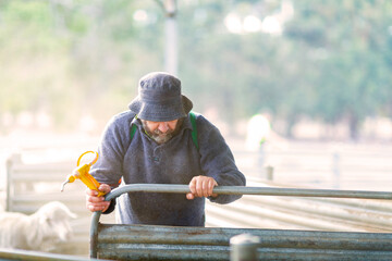 Farmer with floppy hat shutting gate