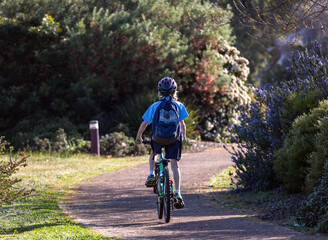 School child with backpack riding bicycle