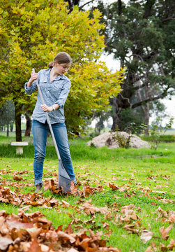 Girls raking fallen autumn leaves in garden