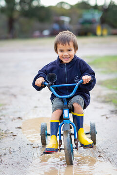 Kid Riding A Tricycle In Puddle