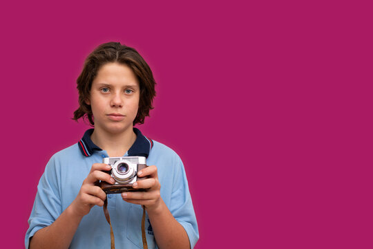 Schoolboy Holding Vintage Camera In Front Of Magenta Background