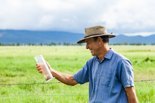 Farmer smiling at rain gauge measurement after storm